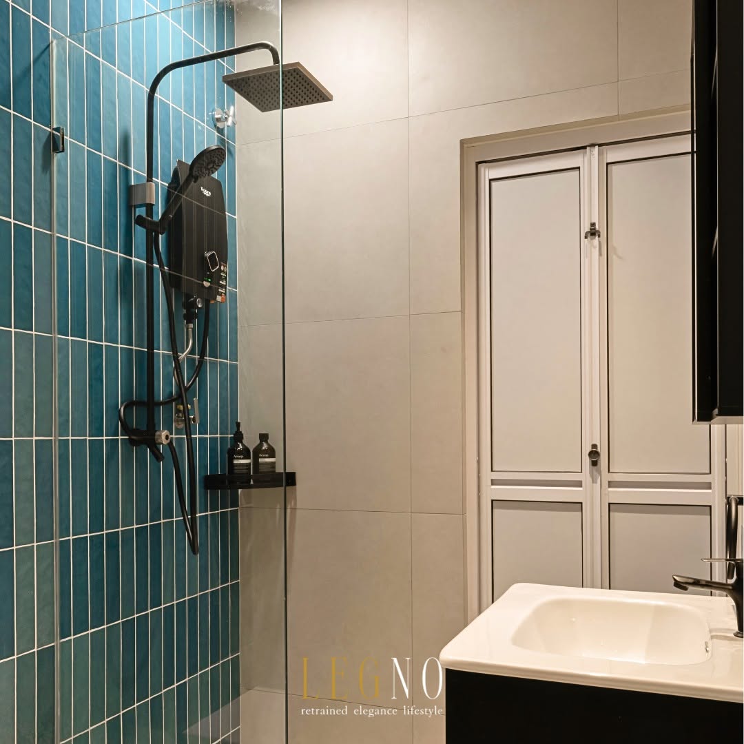Bathroom with teal vertical tiles, glass walk-in shower and black fittings in a Penang terrace house