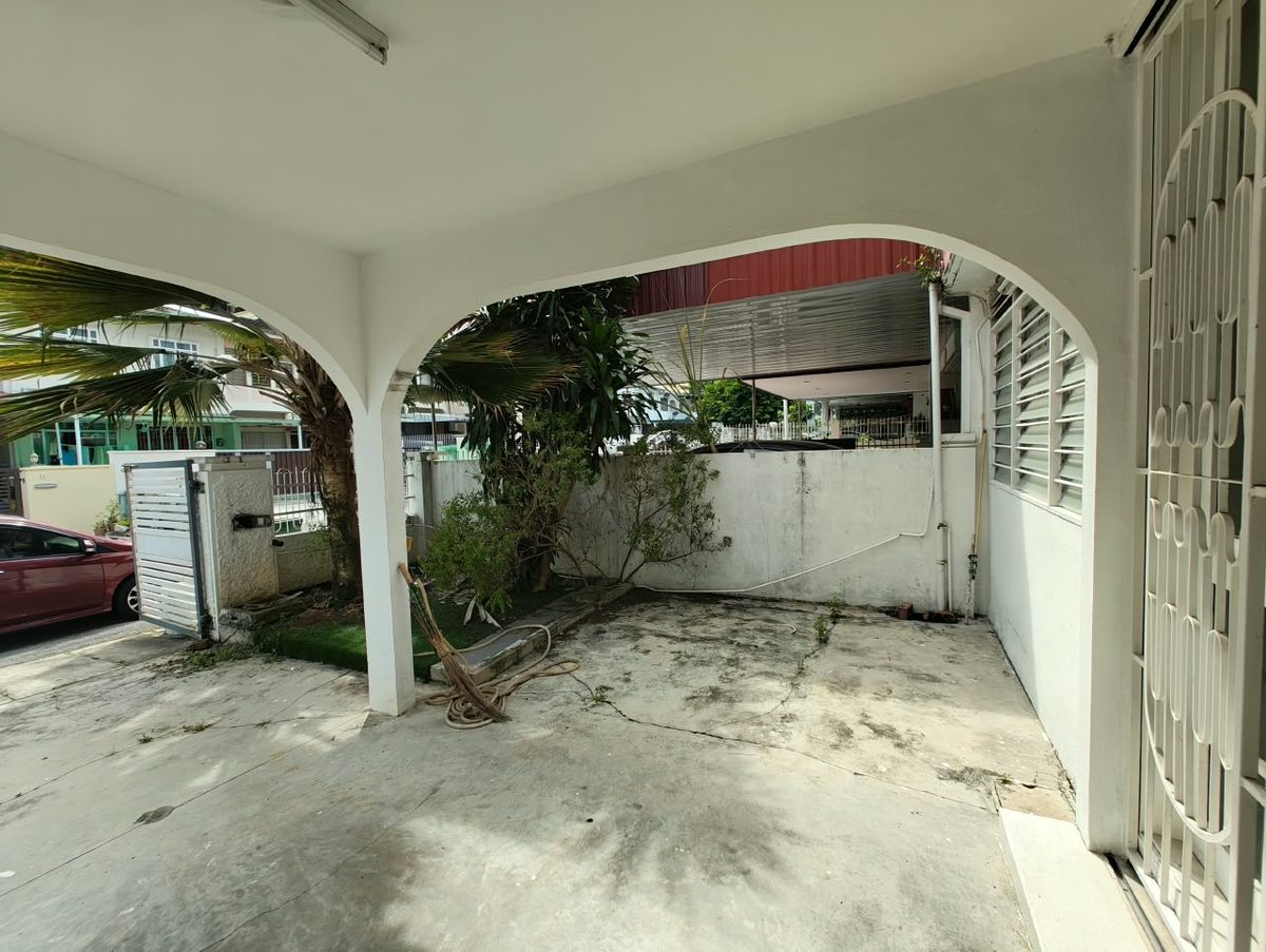 Before renovation: car porch framed by arched columns and overgrown planting at the Penang terrace house