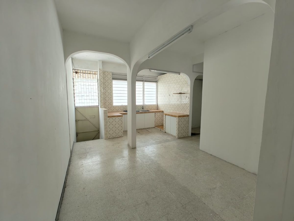 Before renovation: narrow dining and kitchen corridor interrupted by columns and arched openings