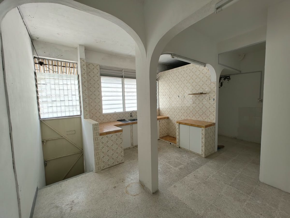 Structural columns and tiled counters blocking sightlines in the original kitchen of a Penang terrace house before reconstruction
