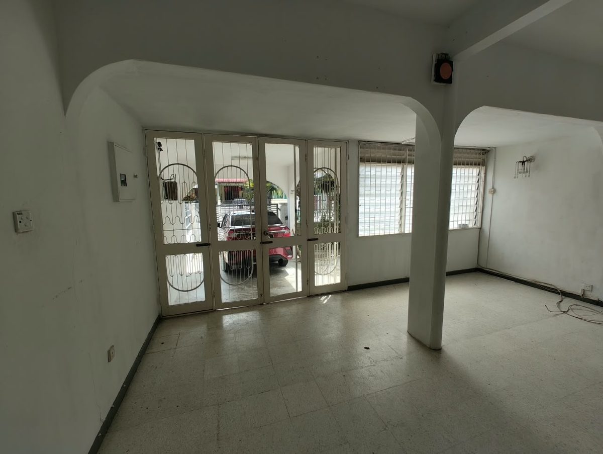 Dark front living room with grille doors and terrazzo flooring before the Penang terrace house reconstruction