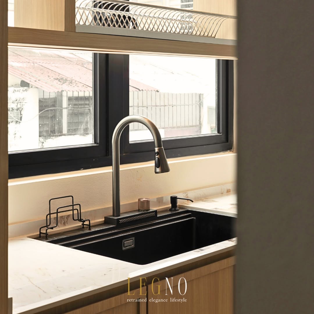 Black granite kitchen sink and pull-out tap set beneath a window for natural light in a Penang kitchen