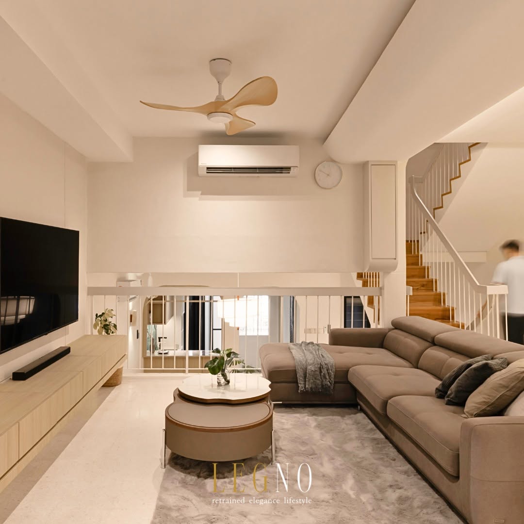 Open-plan living room with sectional sofa and staircase after Penang terrace house renovation by LEGNO